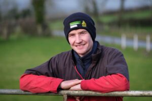 Farmer smiling, leaning on fence with countryside services hat on