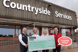 4 people holding a big cheque for 11,500